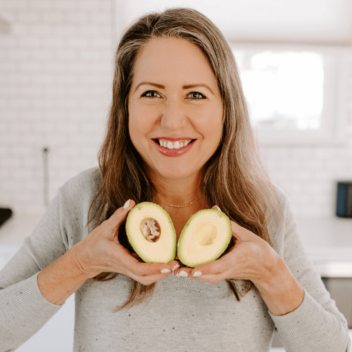 Amy holding a cut avocado like a heart.