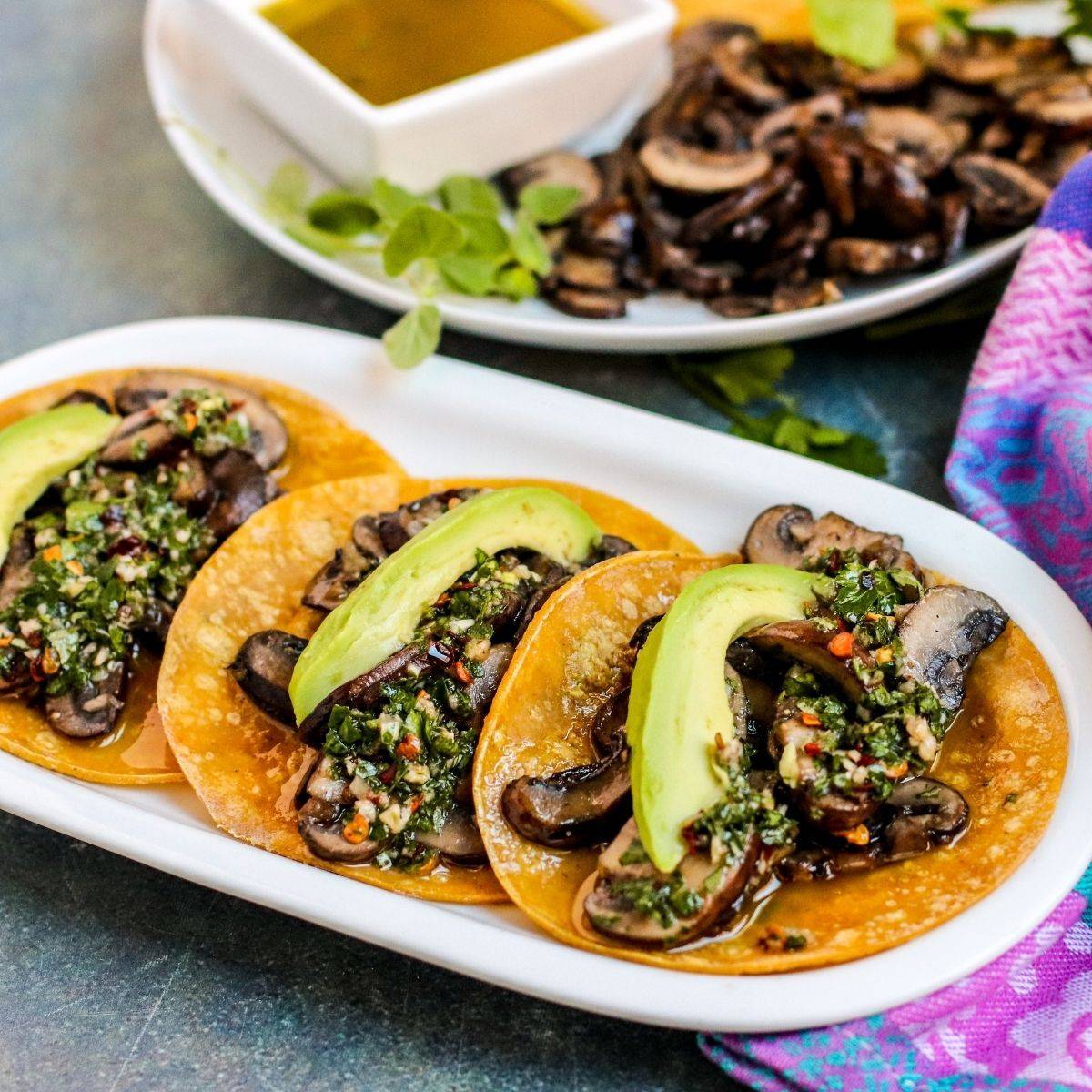 Mushroom tacos topped with chimichurri and sliced avocado.