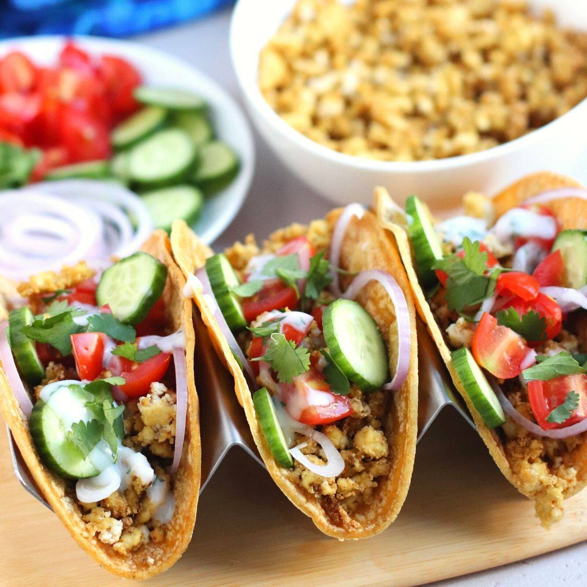 Tacos made with baked tofu crumbles, cucumbers, tomatoes, red onions, cilantro, and garlicky vegan yogurt sauce.
