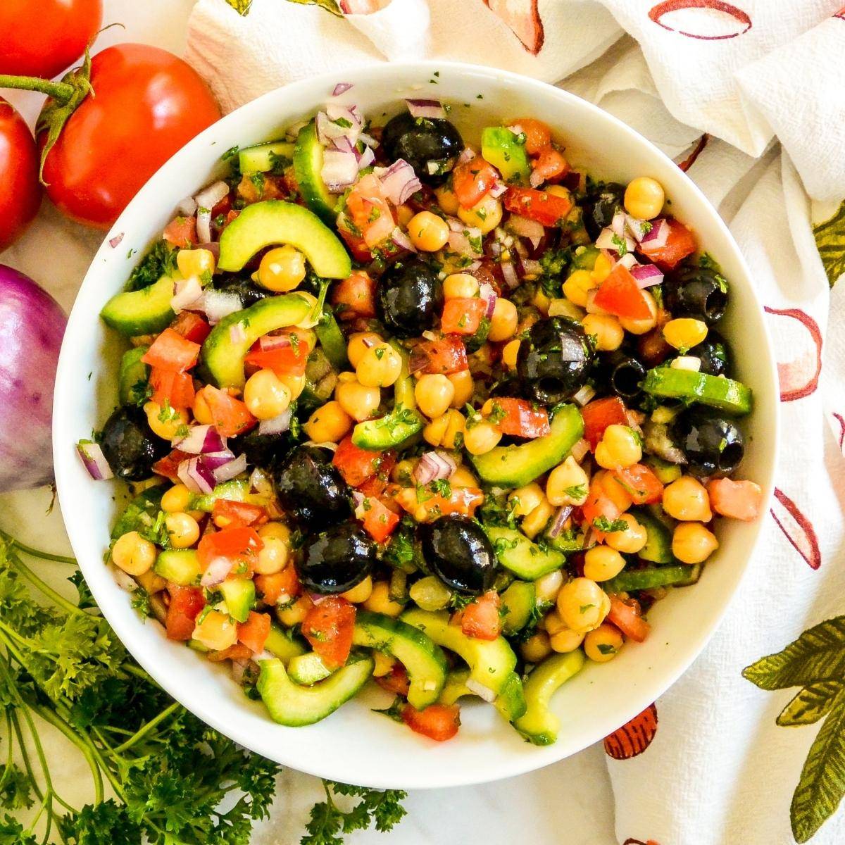 Bowl of Mediterranean chickpea cucumber salad with olives and tomatoes.