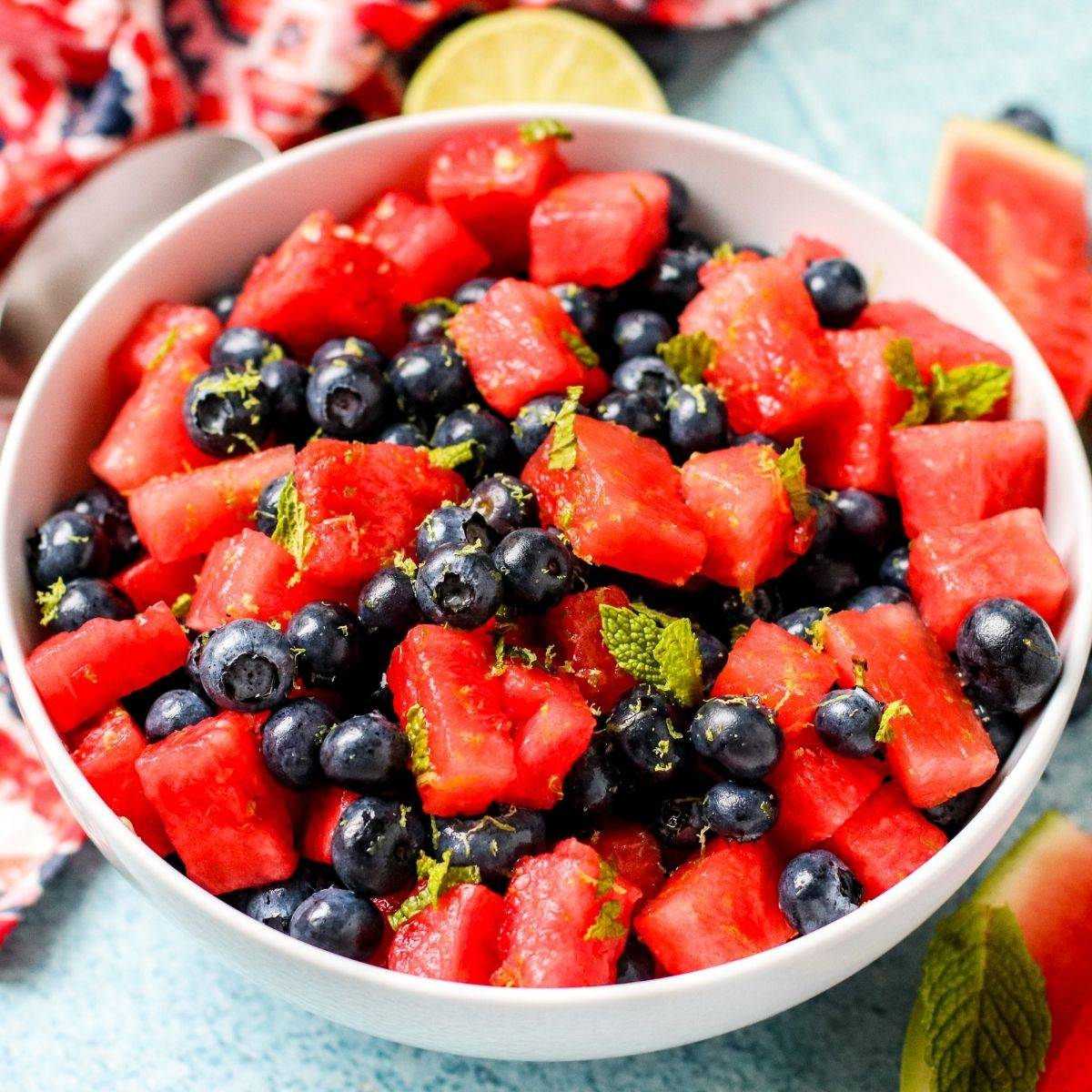 Bowl of watermelon blueberry salad with mint leaves and lime zest.