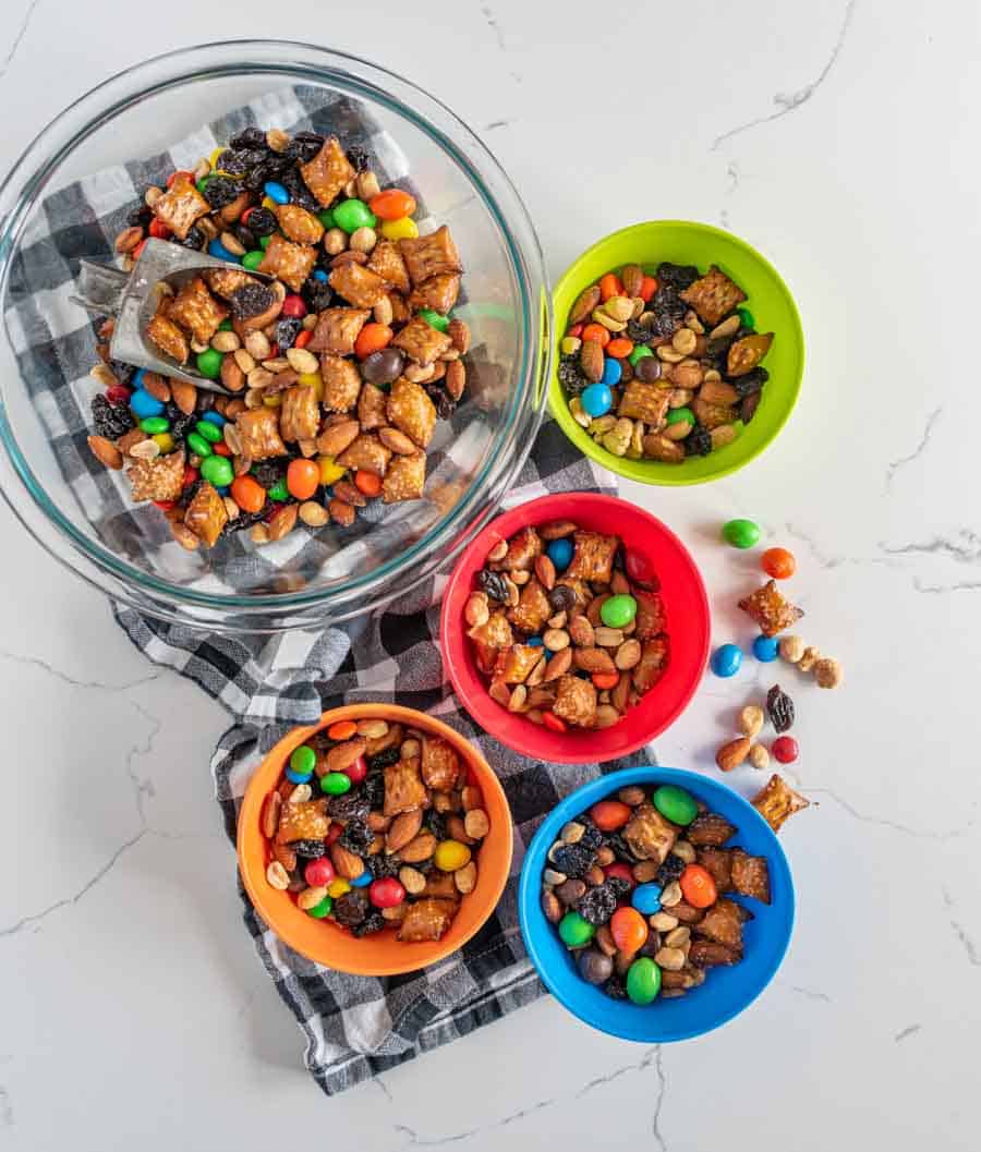 trail mix in different colored bowls on blue and white towel.