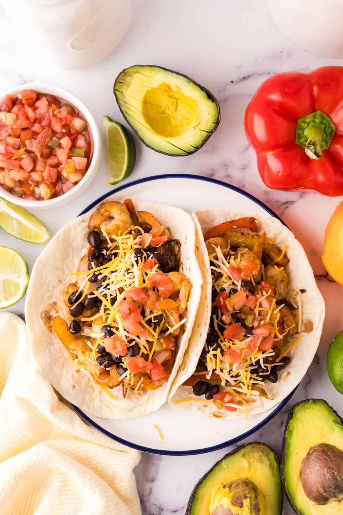 shrimp tacos on white plate with toppings spread around.