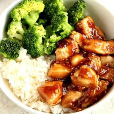 Chicken with teriyaki sauce, rice and broccoli in a white bowl.