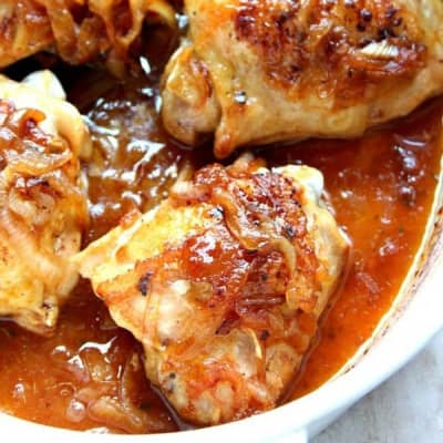 Roasted chicken thighs with onions in a baking dish.