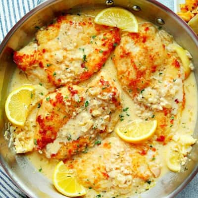 Chicken breasts in lemon sauce in a pan.