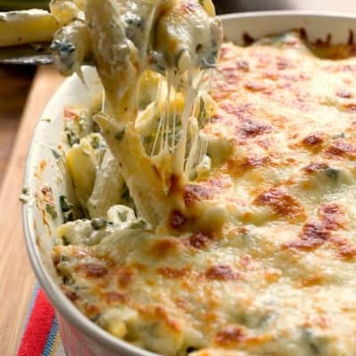 Penne pasta with spinach and chicken in an oval baking dish.