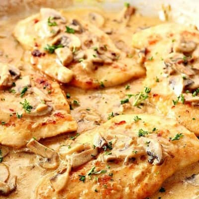 Chicken cutlets in creamy mushroom sauce in a skillet.