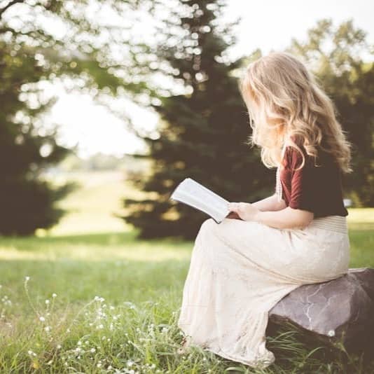 woman sitting while reading book