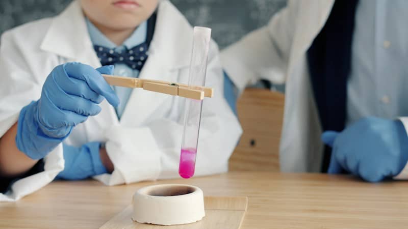Children in lab coats conduct a science experiment.