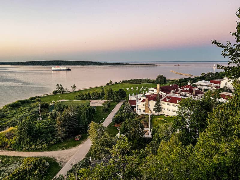 View of a boat in the Straits of Mackinac as the sun is setting with a bird's eye view of Mission Point Resort on Mackinac Island..