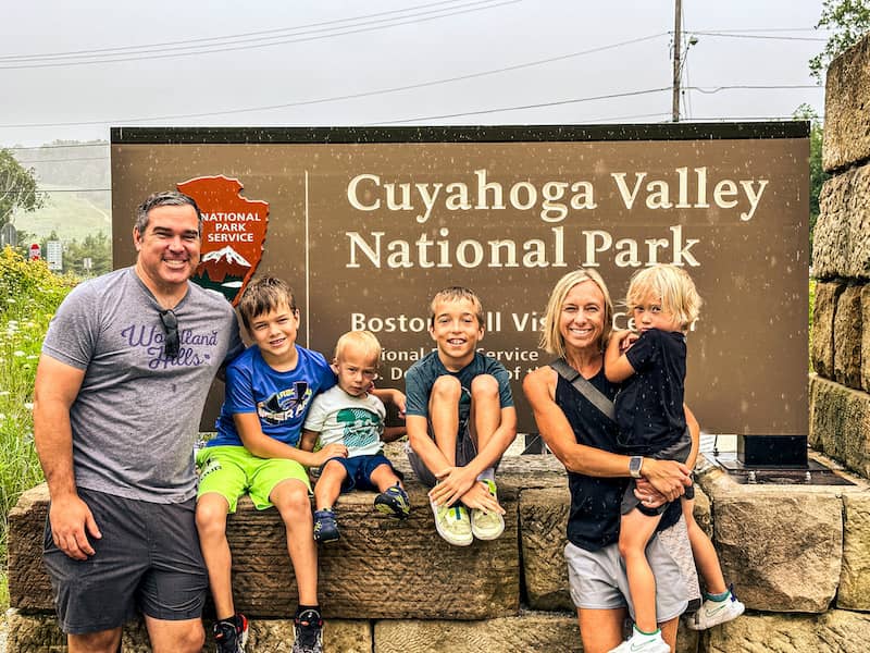 Mom and Dad with four boys smiling in front of the brown sign for Cuyahoga Valley National Park