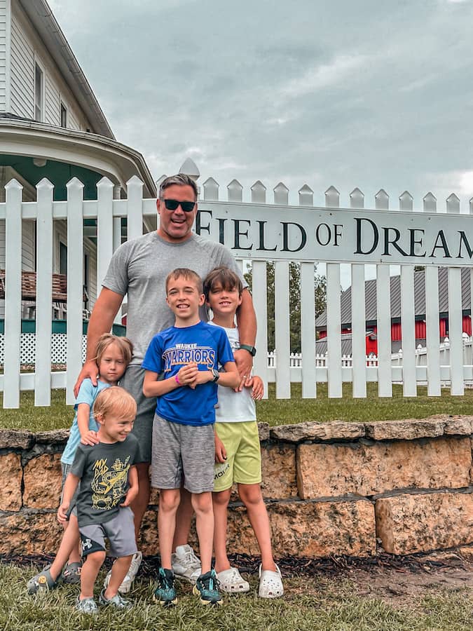 Family standing in front of the Field of Dreams sign in Dyersville, Iowa