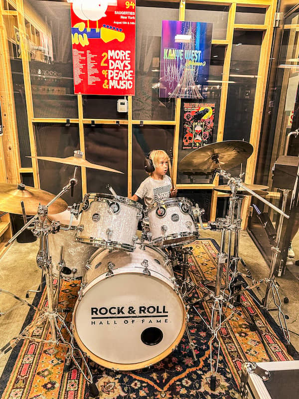 Young boy wearing headphones and sitting at a drum set at the Rock & Roll Hall of Fame in Cleveland, Ohio