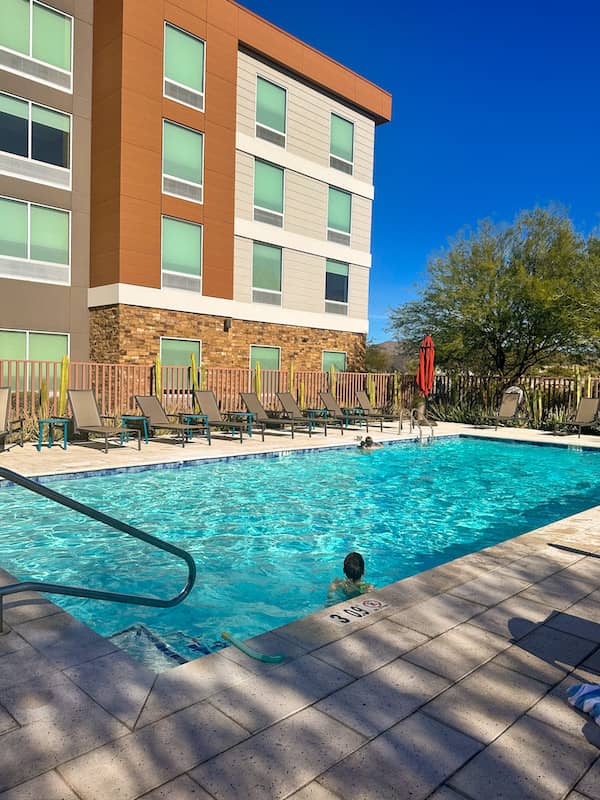 Outdoor pool area at Home2 Suites by Hilton Mesa Longbow in Arizona with lounge chairs and clear blue sky.
