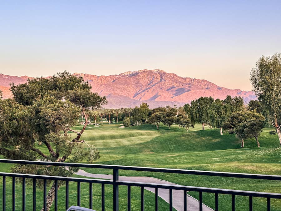 View overlooking golf course with the sunset's pink colors on the mountains in the background.