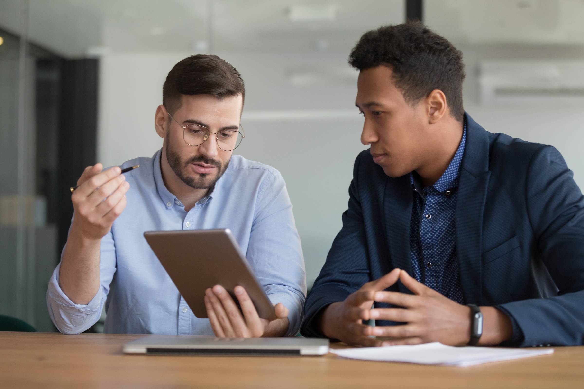 two men look at a tablet screen