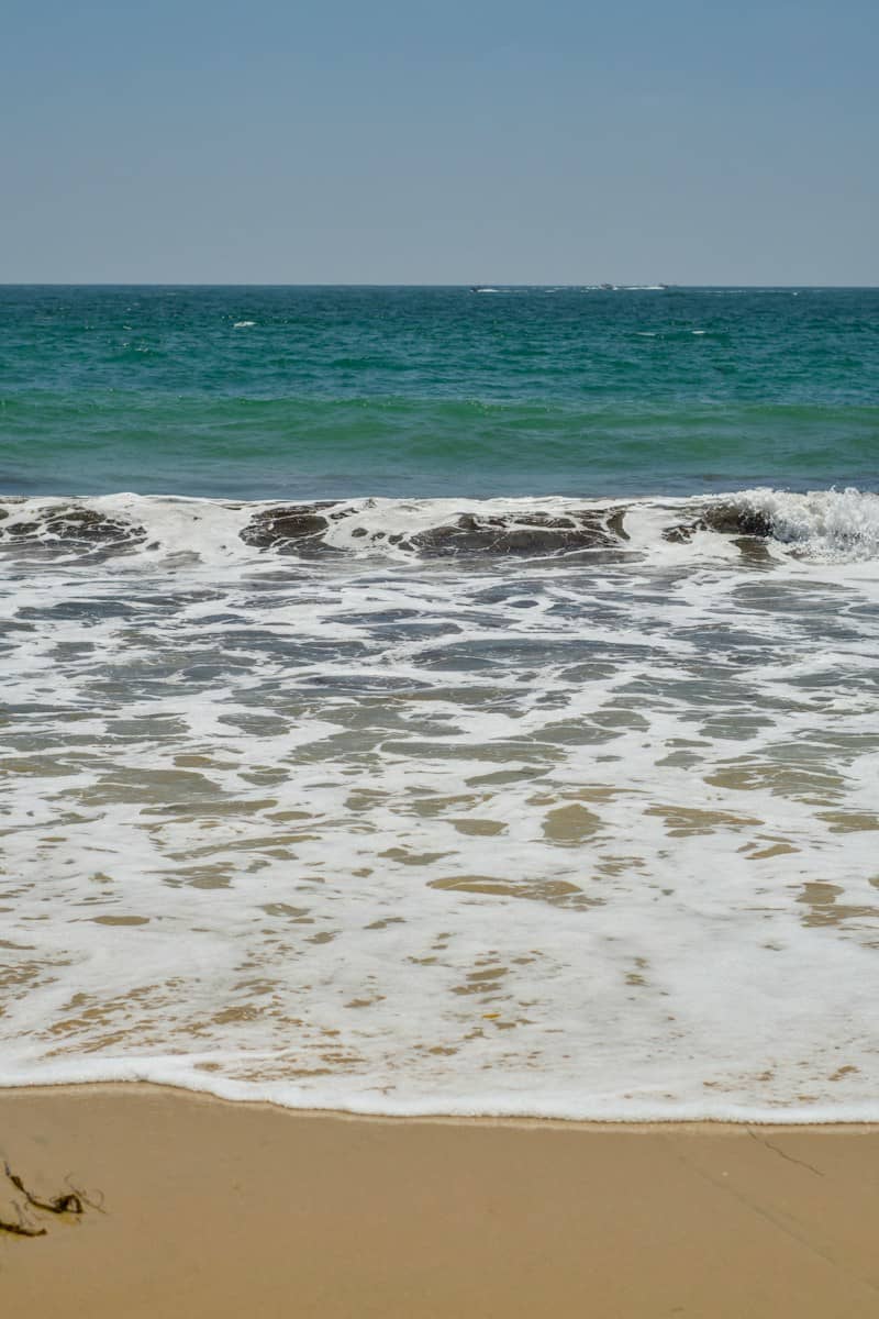 A person walking along the beach with a surfboard