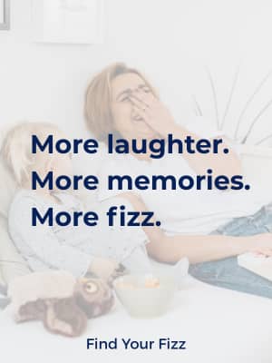 Woman and young girl sitting together on a couch laughing, with text overlay reading “More laughter. More memories. More fizz. Find Your Fizz.”