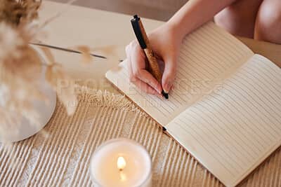 A woman writes in a notebook beside a lit candle, creating a quiet, reflective moment for journaling and self-reflection.