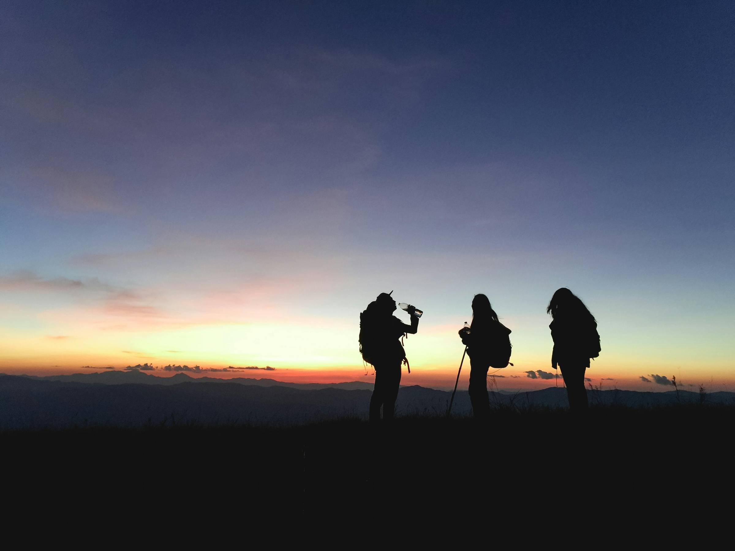 Silhouettes of three hikers in the dusk