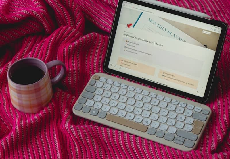 A keyboard and a cup of coffee on a blanket