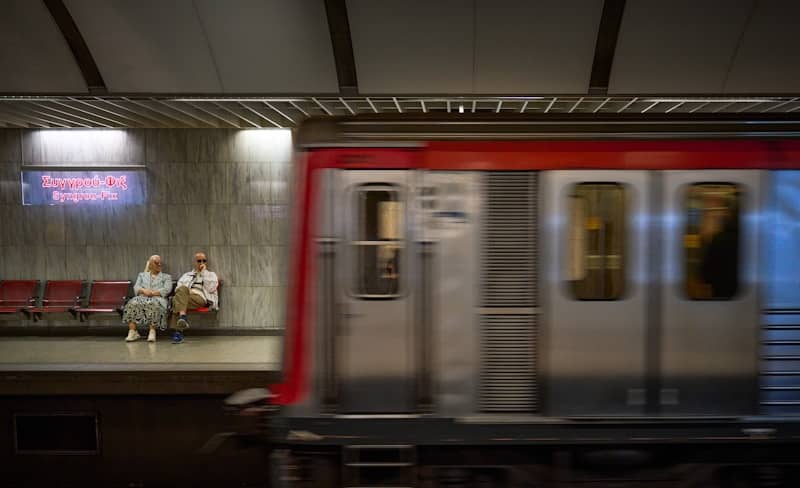 Two people wait on a subway platform as train passes