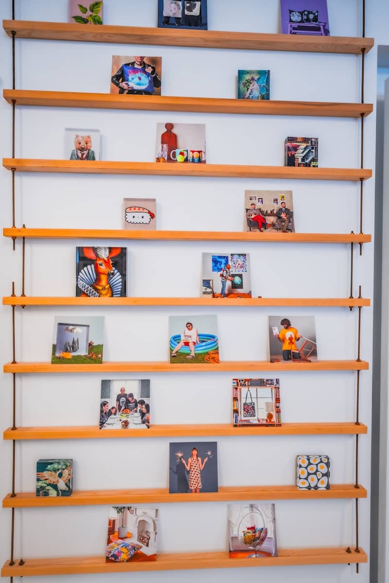 A wall with multiple wooden shelves displaying various small pictures.