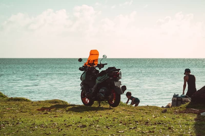 Scooter, person, and child by the calm ocean.