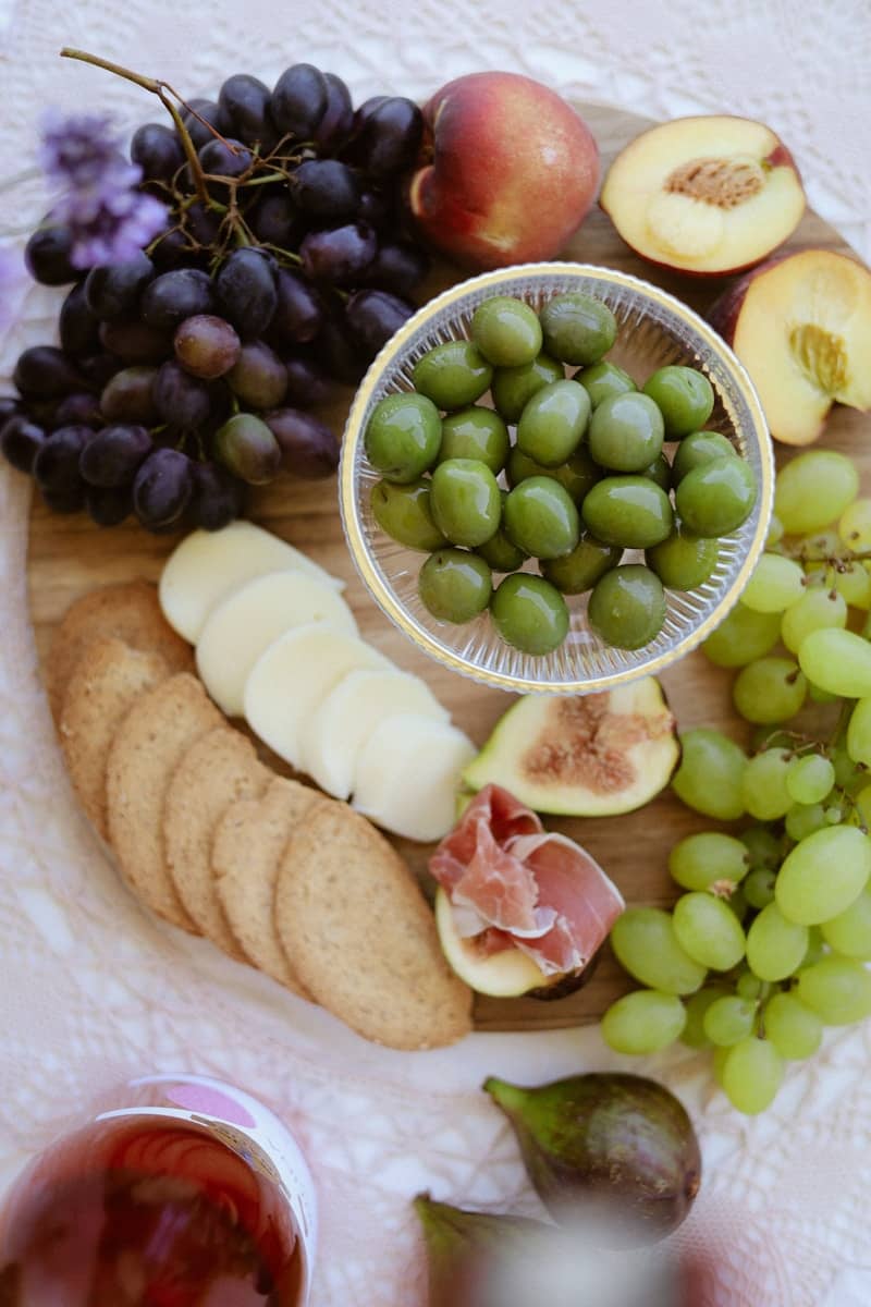 A delicious board with fruits, olives, and crackers.