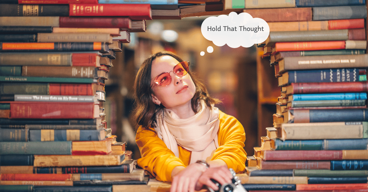 A young woman stares out through a circular opening made of strategically placed books.