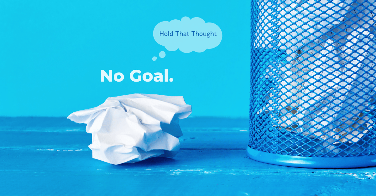 A crumpled white paper rests on a blue table next to a blue metal waste bin. Text reads "No Goal." with a Hold That Thought bubble above it.