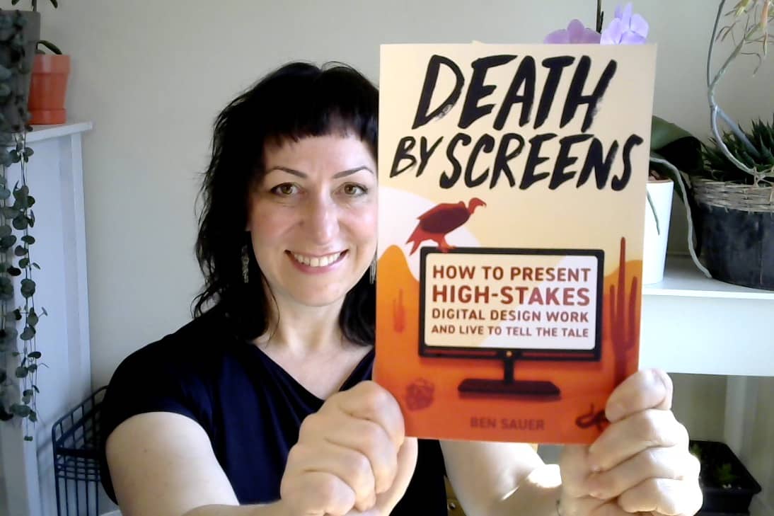 Kim is smiling and holding up the book Death by Screens