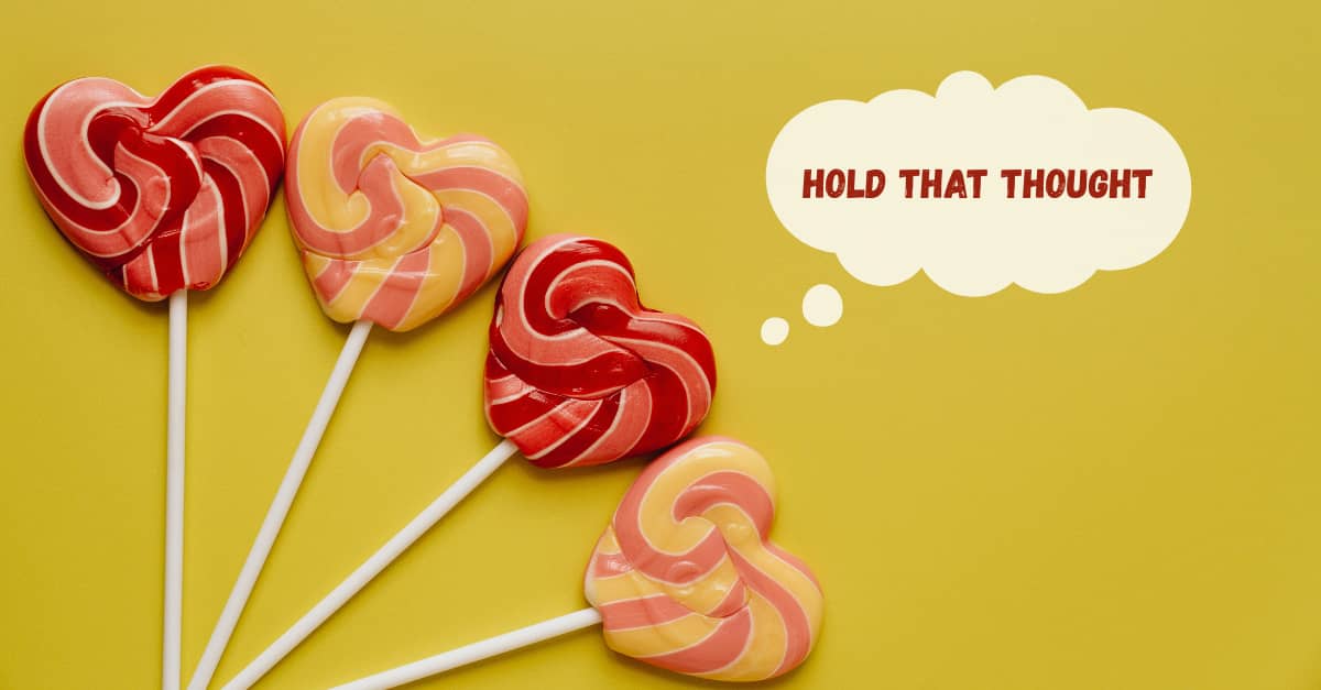 Four heart shaped lollipops against a mustard yellow background.