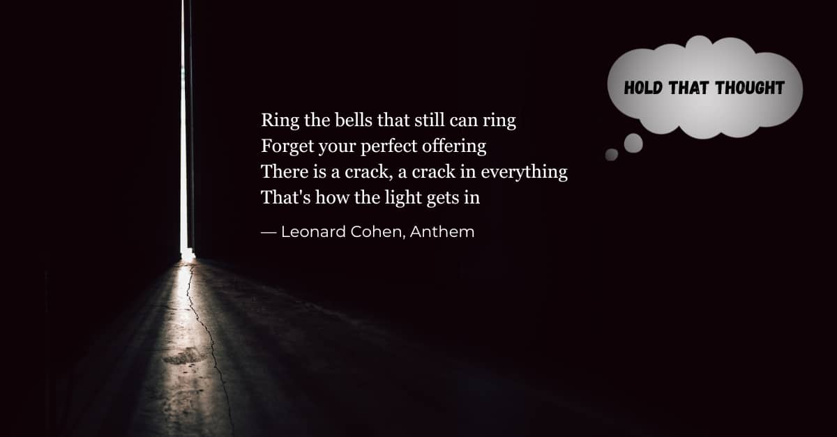 A dark room with a door open a small crack, letting light in. A verse from Leonard Cohen's Anthem is in white on the wall.