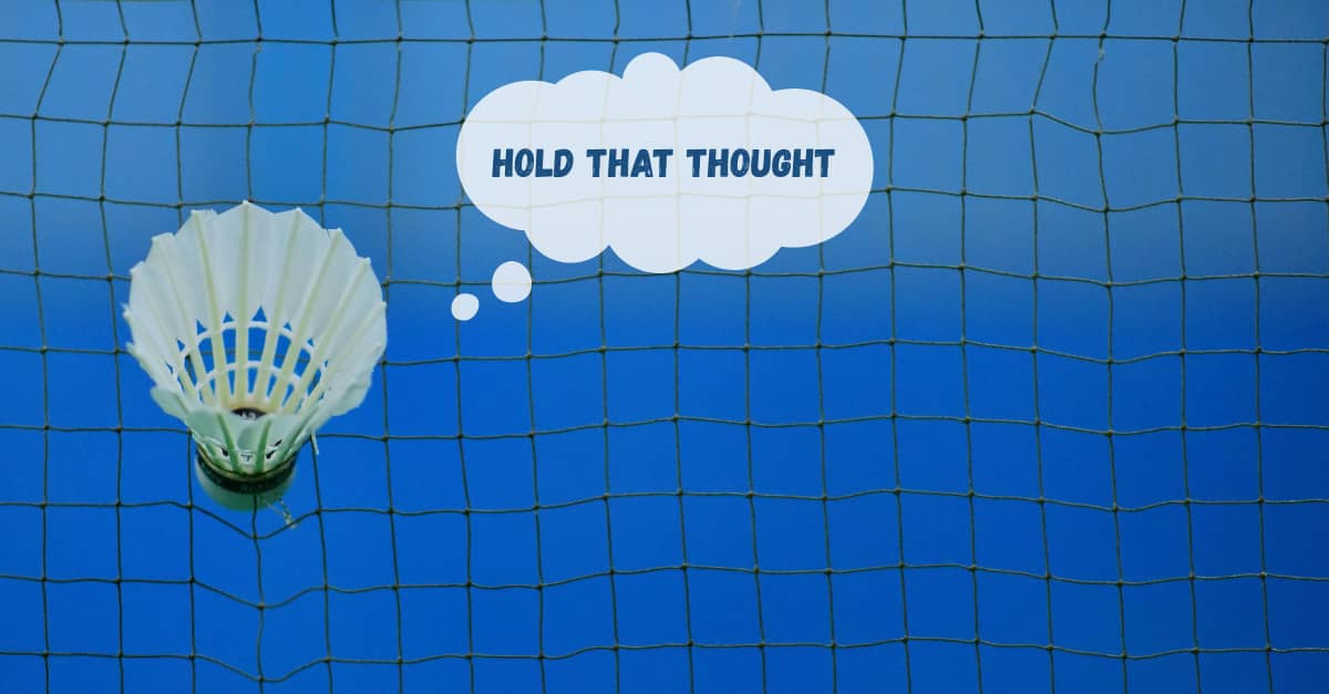 A shuttlecock stuck in a badminton net against a blue sky.