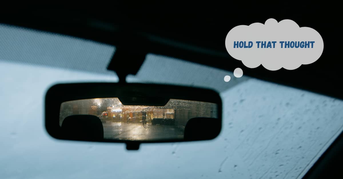  Perspective from inside a car on a gloomy day, with focus on rearview mirror. 