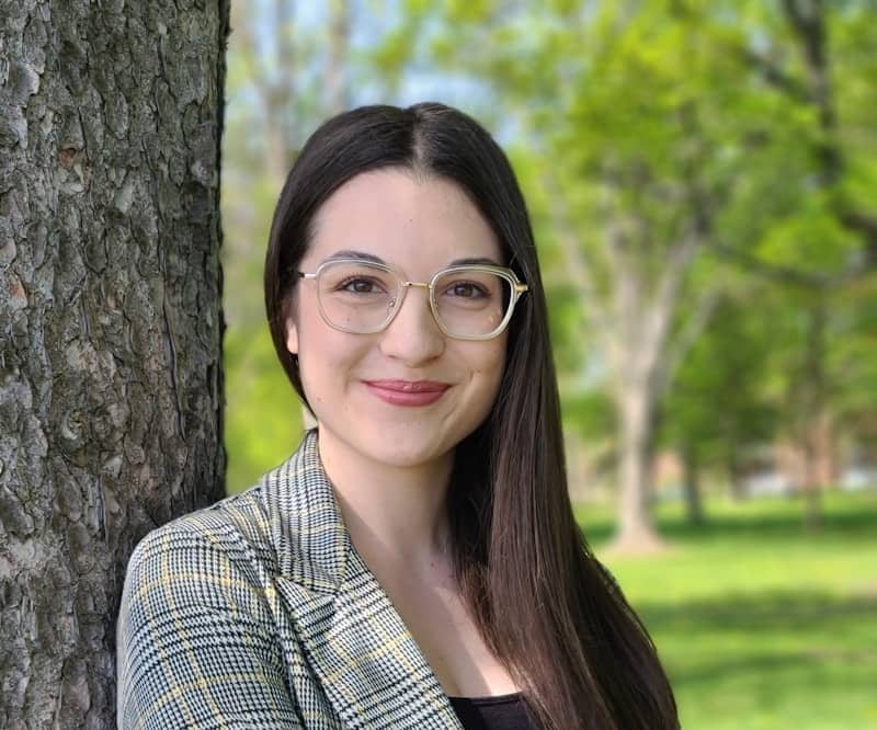 A woman standing next to a tree in a park