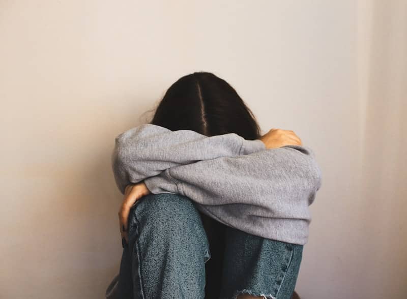 a woman sitting on the floor with her arms wrapped around her head