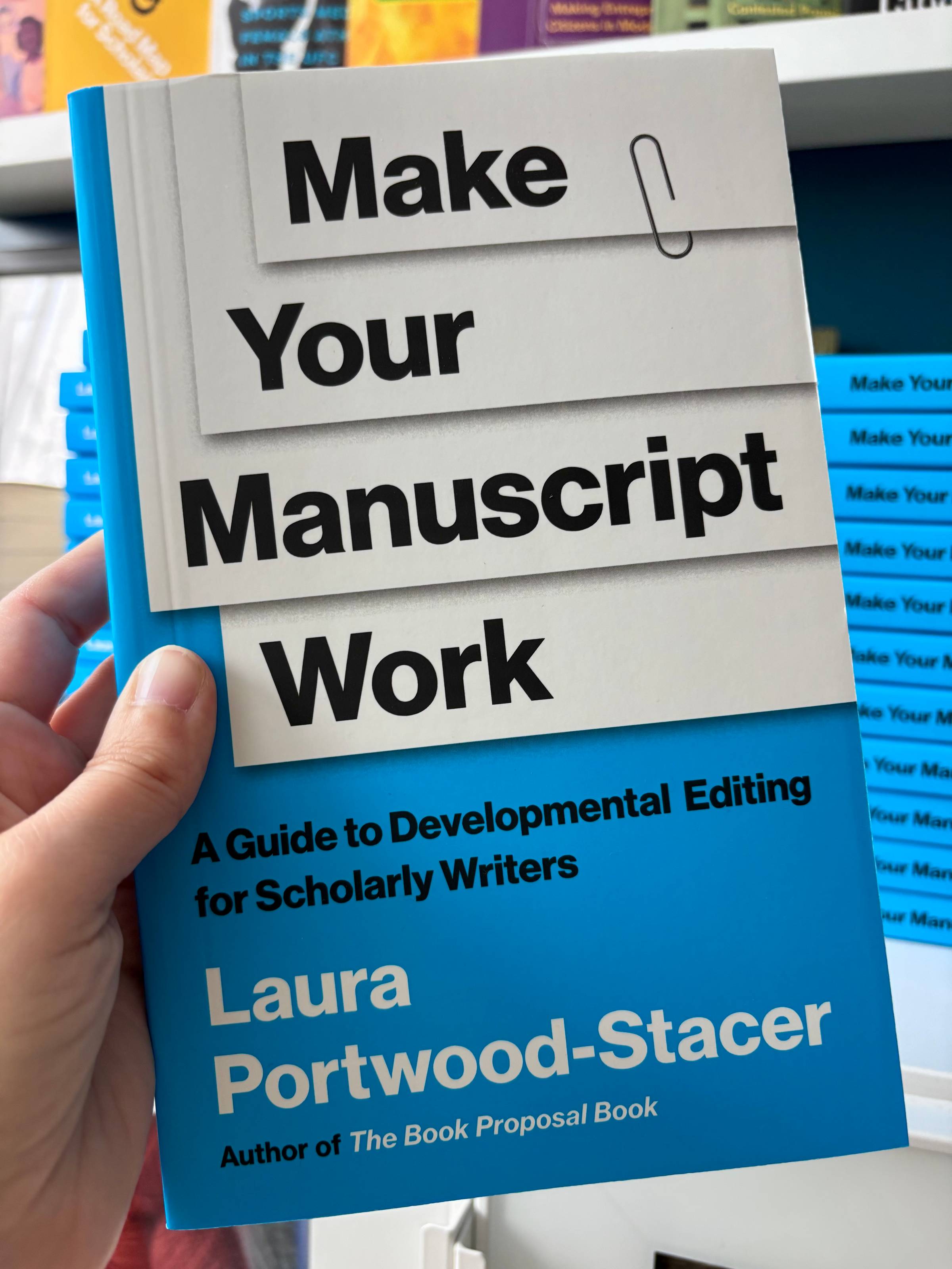 A hand holding a paperback copy of Make Your Manuscript Work: A Guide to Developmental Editing for Scholarly Writers, by Laura Portwood-Stacer, author of The Book Proposal Book