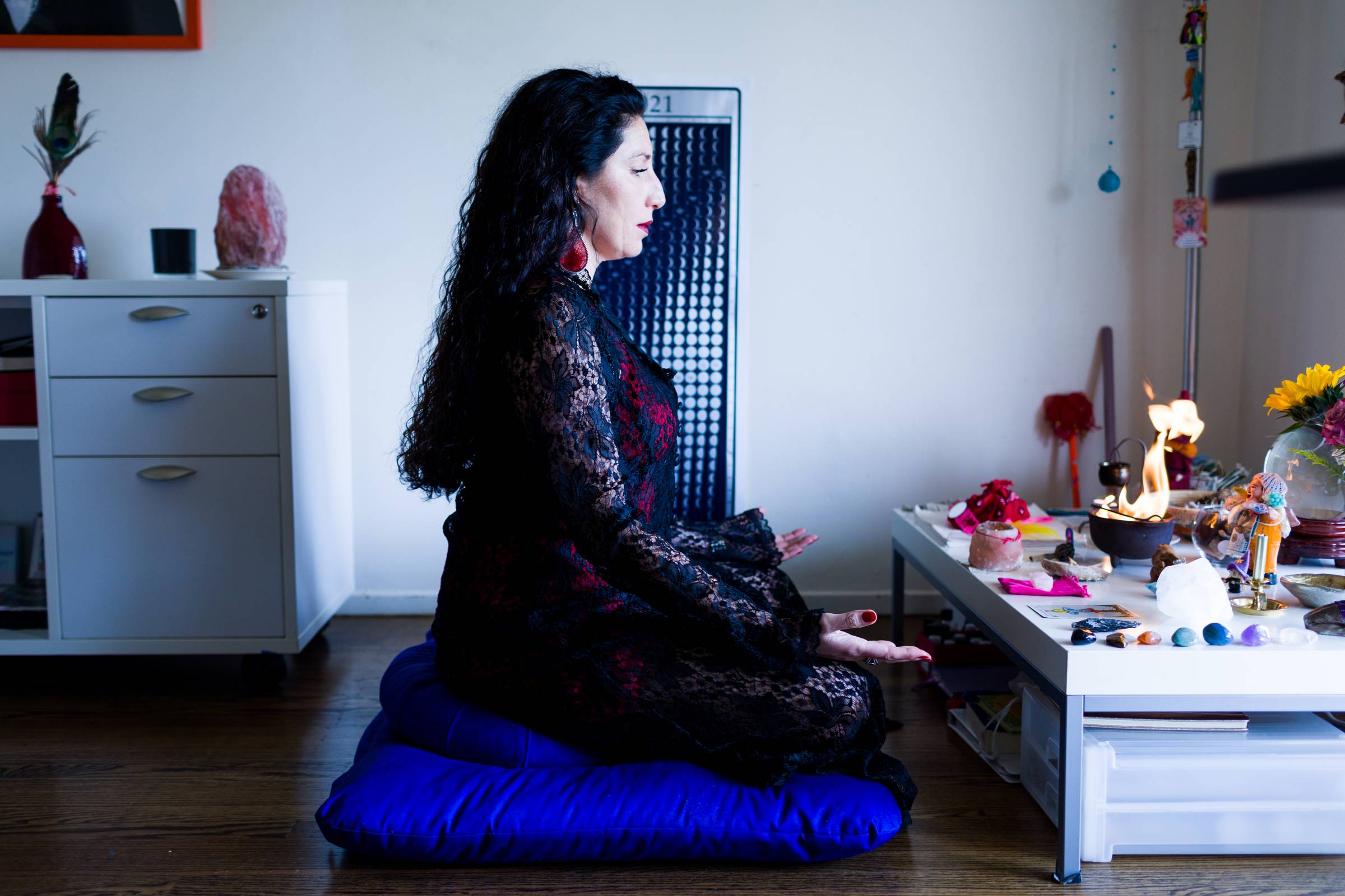 Maritza Schafer Woman meditating beside a lit altar with crystals and candles in a spiritual practice space