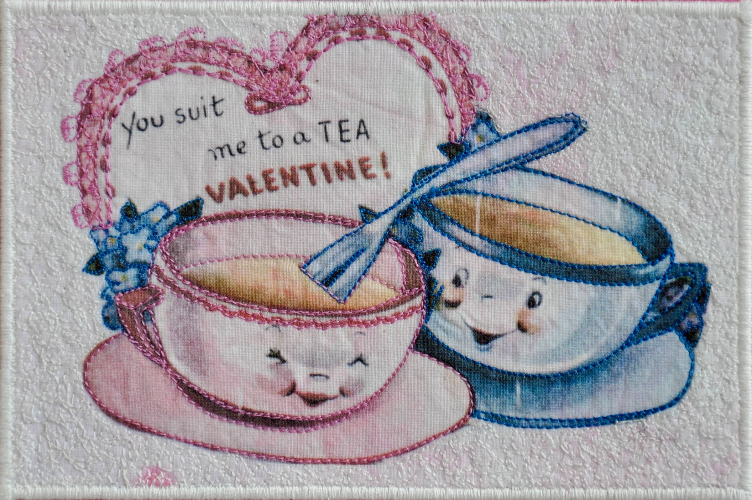 Two quilted tea cups stitched in fabric, with the phrase “you suit me to a tea” embroidered on top of them.
