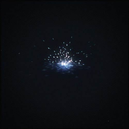 gif of blue sparks flying from middle of infinite black space