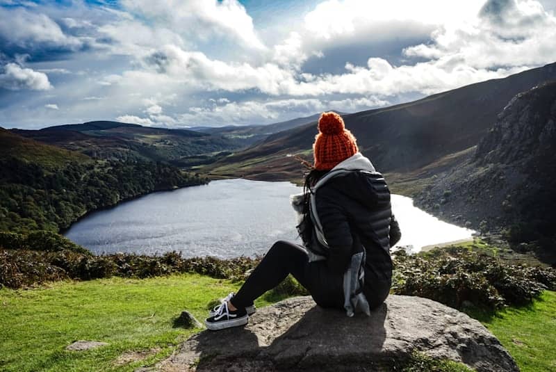 woman wearing black jacket sitting on rock