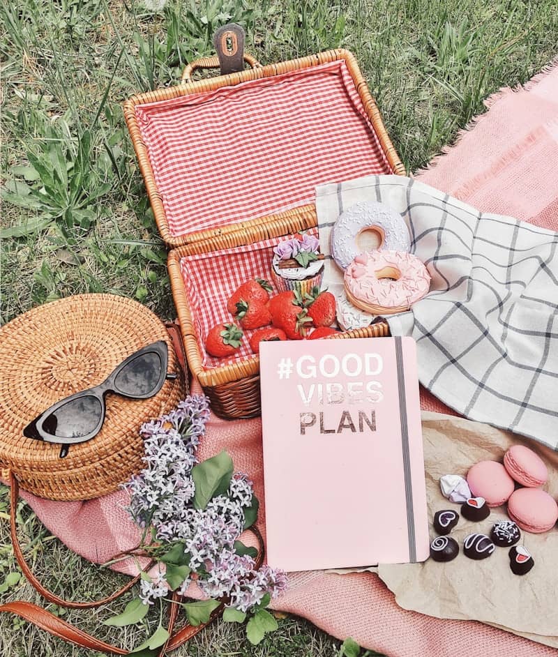 Picnic basket with strawberries, donuts, macarons, and sunglasses.