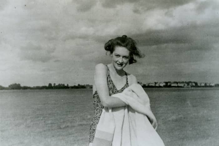 Fotografía en blanco y negro de una joven sonriente en la orilla del mar, con bañador y una toalla en el brazo: la imagen que se hizo pasar por la novia de «Martin».