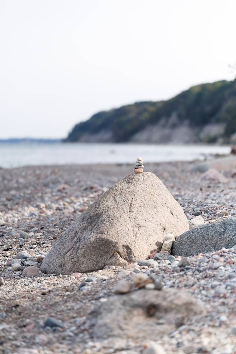 Stacked stones balanced on a large rock at the beach.