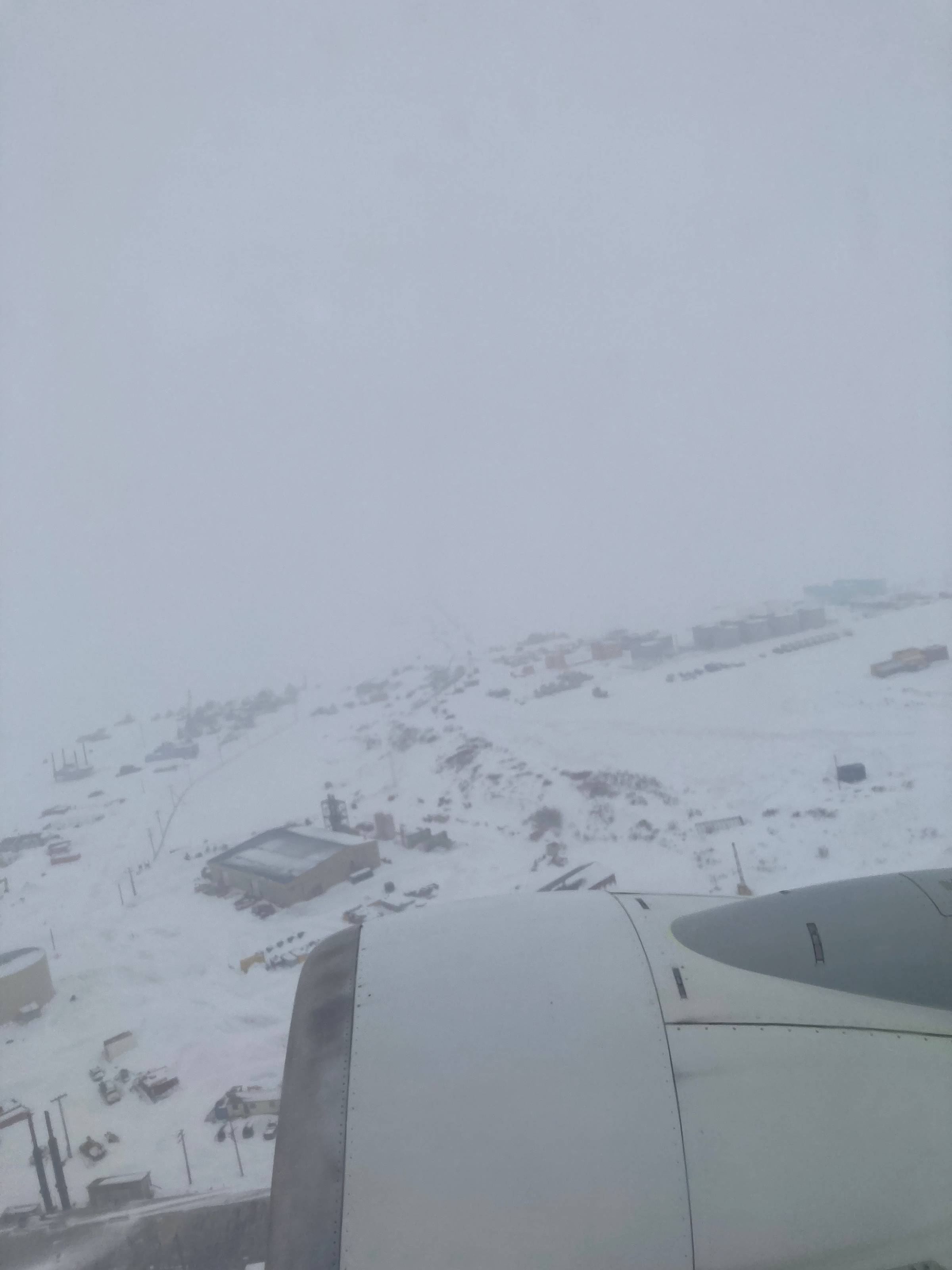 Looking down at Nome, Alaska from a departing plane, streets and buildings visible through a cover of snow.