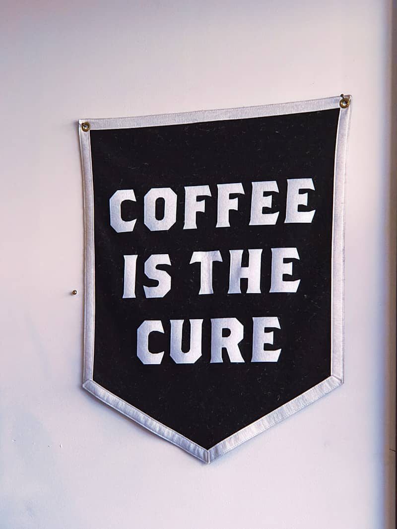 A black banner with "coffee is the cure" text.