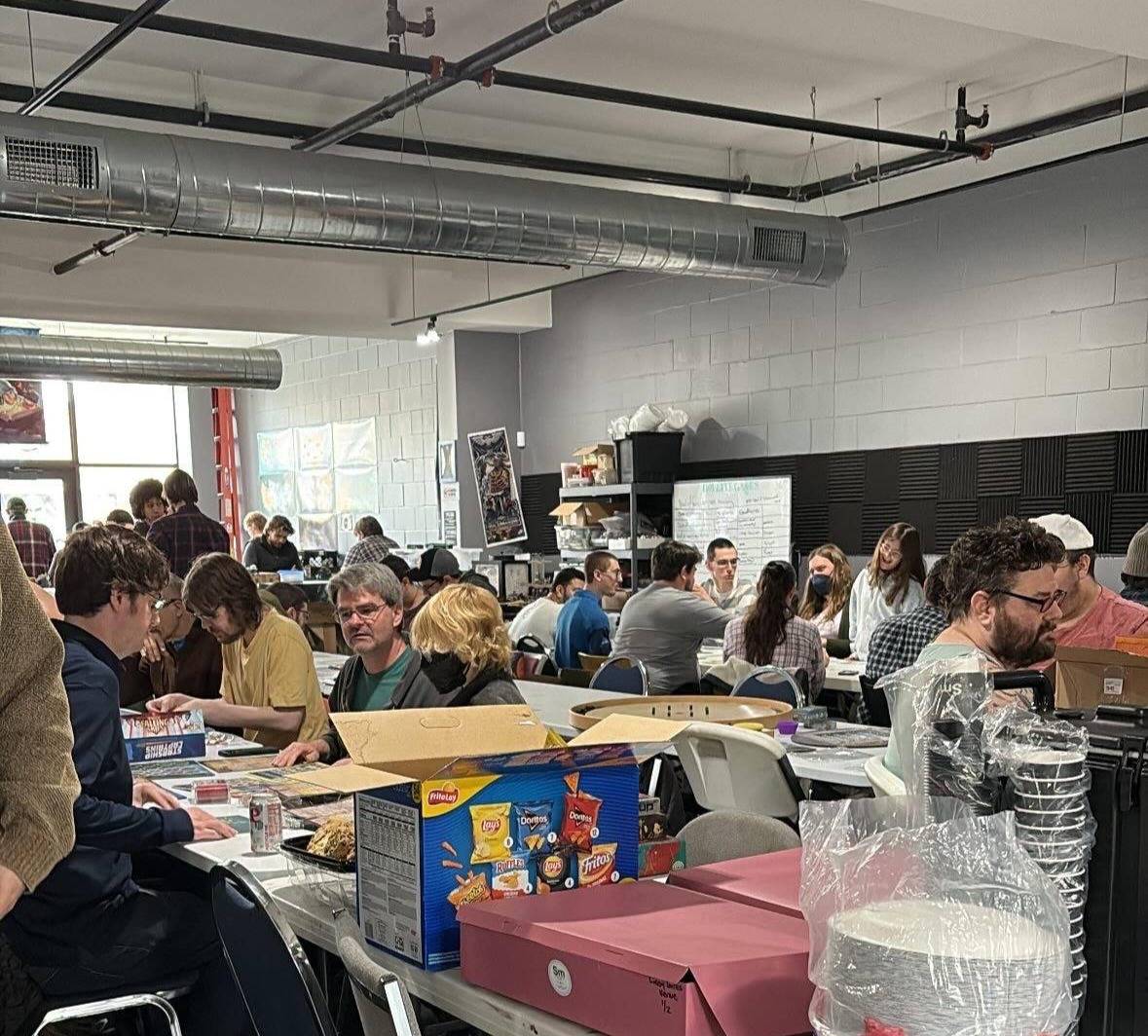People sitting in groups at different tables playing board games